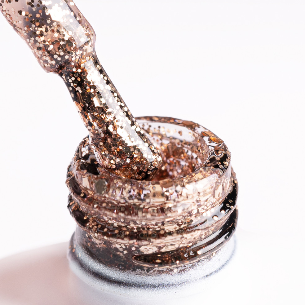 Pędzelek zanurzony w złotym brokatowym lakierze z drobinkami różnej wielkości