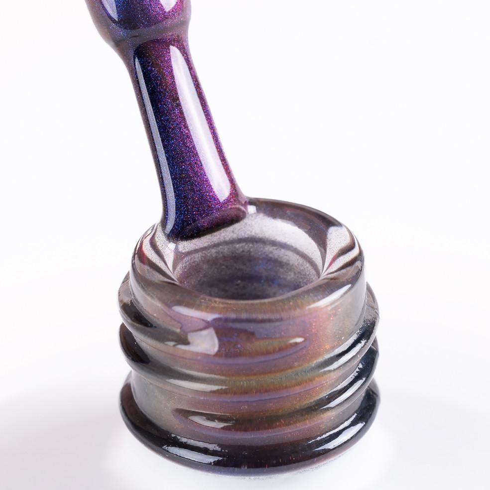 Szyjka butelki i oparty o nią pędzelek zanurzony w dwykolorowym lakierze hybrydowym z efektem cat eye Szyjka butelki i oparty o nią pędzelek zanurzony w dwykolorowym lakierze hybrydowym z efektem cat eye