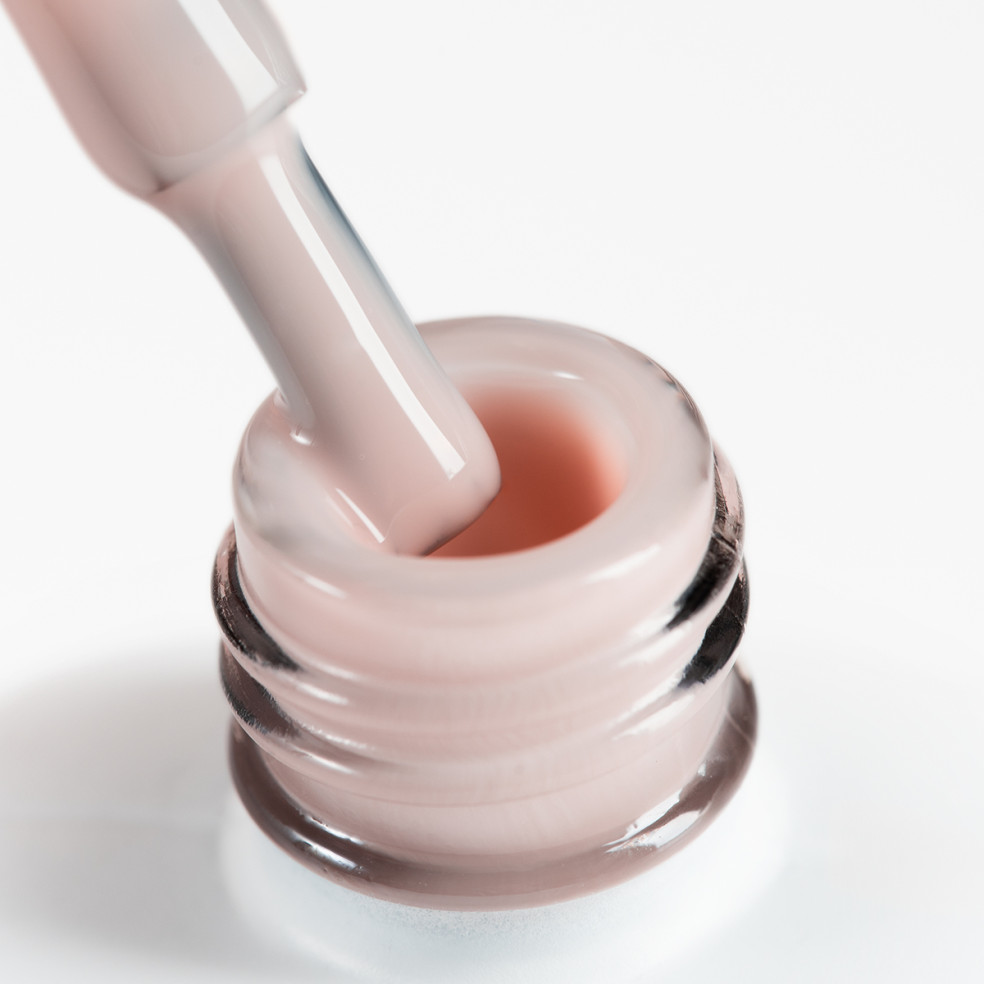 Pędzelek zanurzony w beżowym żelu w butelce