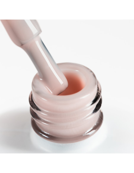 Pędzelek zanurzony w beżowym żelu w butelce