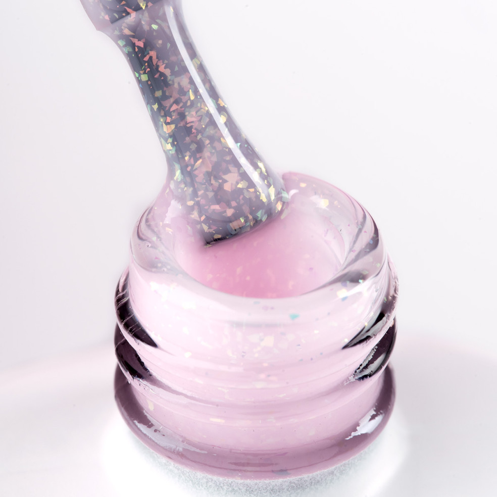 Pędzelek zanurzony w różowym żelu do przedłużania paznokci z opalizującymi drobinkami
