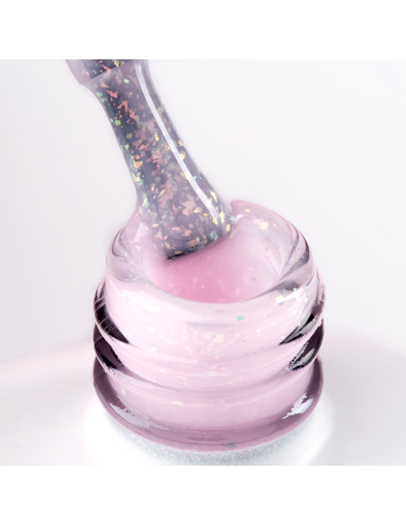 Pędzelek zanurzony w różowym żelu do przedłużania paznokci z opalizującymi drobinkami