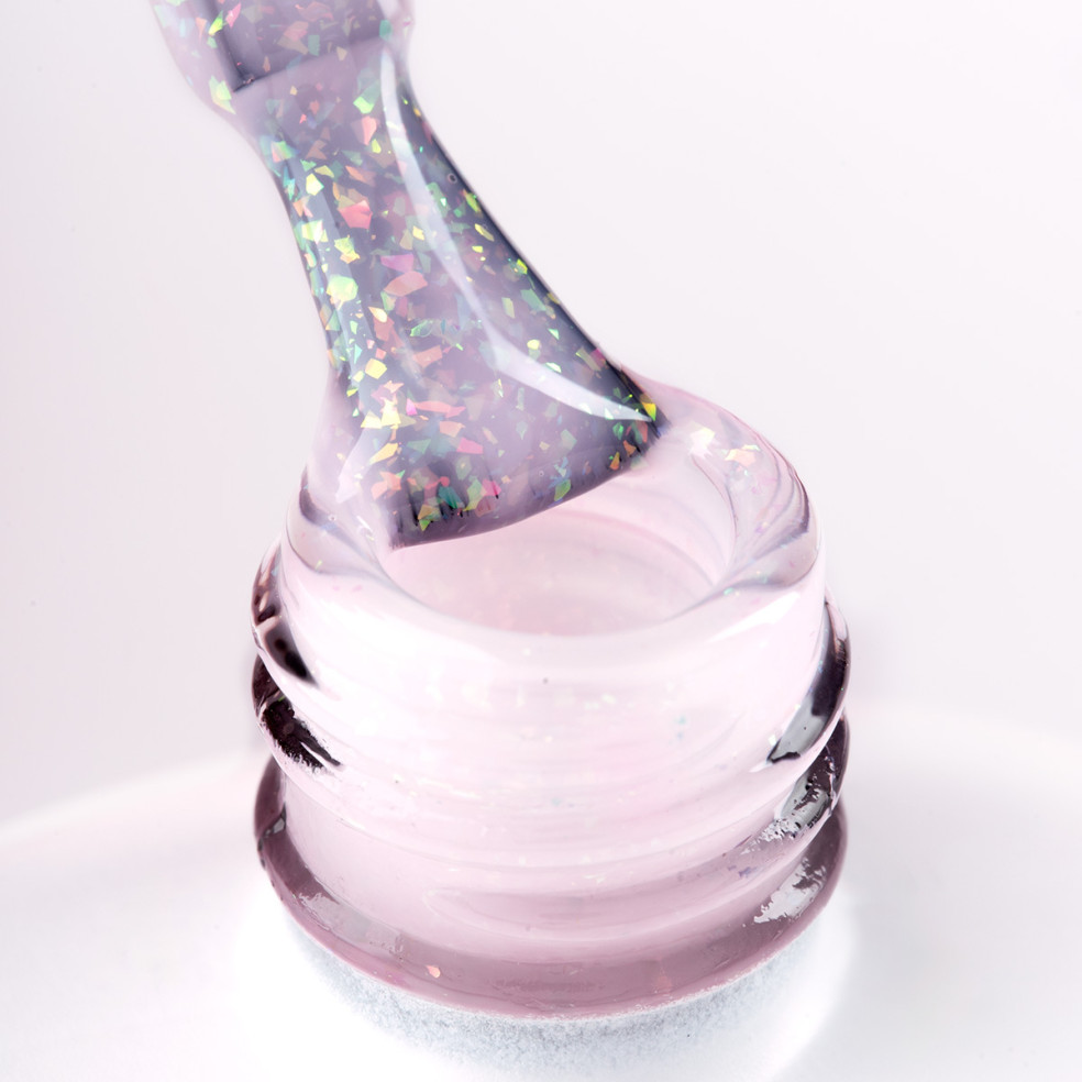 Pędzelek zanurzony w różowym żelu do przedłużania paznokci z wielobarwnymi drobinkami