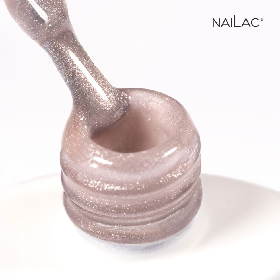 Pędzelek zanurzony w brokatowym lakierze hybrydowym cat eye porcelain effect w kolorze różowym  oparty o szyjkę butelki