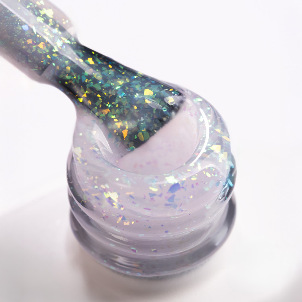 Pędzelek zanurzony w żelu do przedłużania paznokci w kolorze mlecznobialym z kawałkami ciętej folii