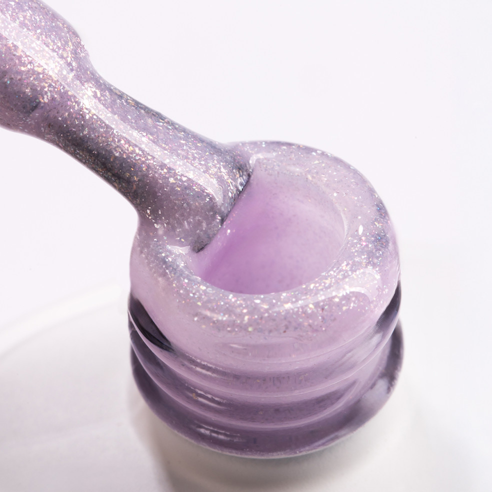 Pędzelek zanurzony w żelu do przedłużania paznokci w kolorze mlecznofioletowym z drobinkami brokatu