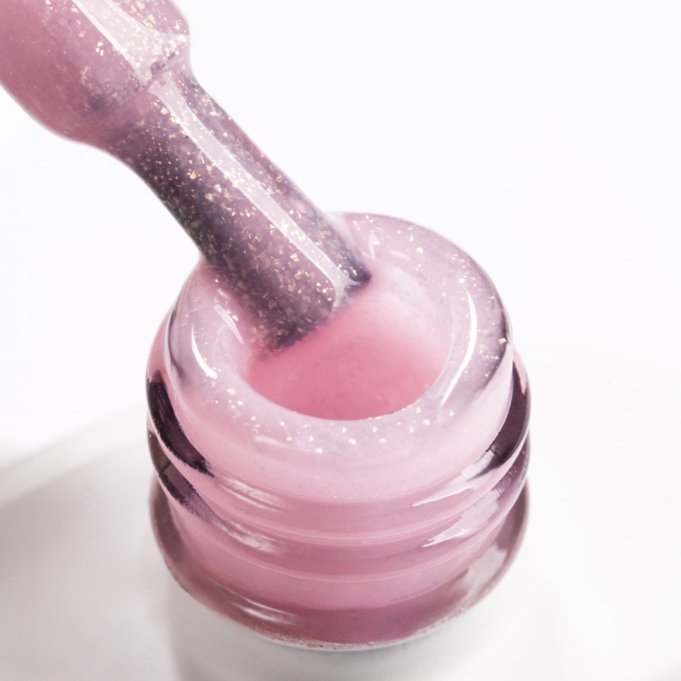 Pędzelek zanurzony w brzoskwiniowo różowym żelu do przedłużania paznokci z brokatowymi drobinkami