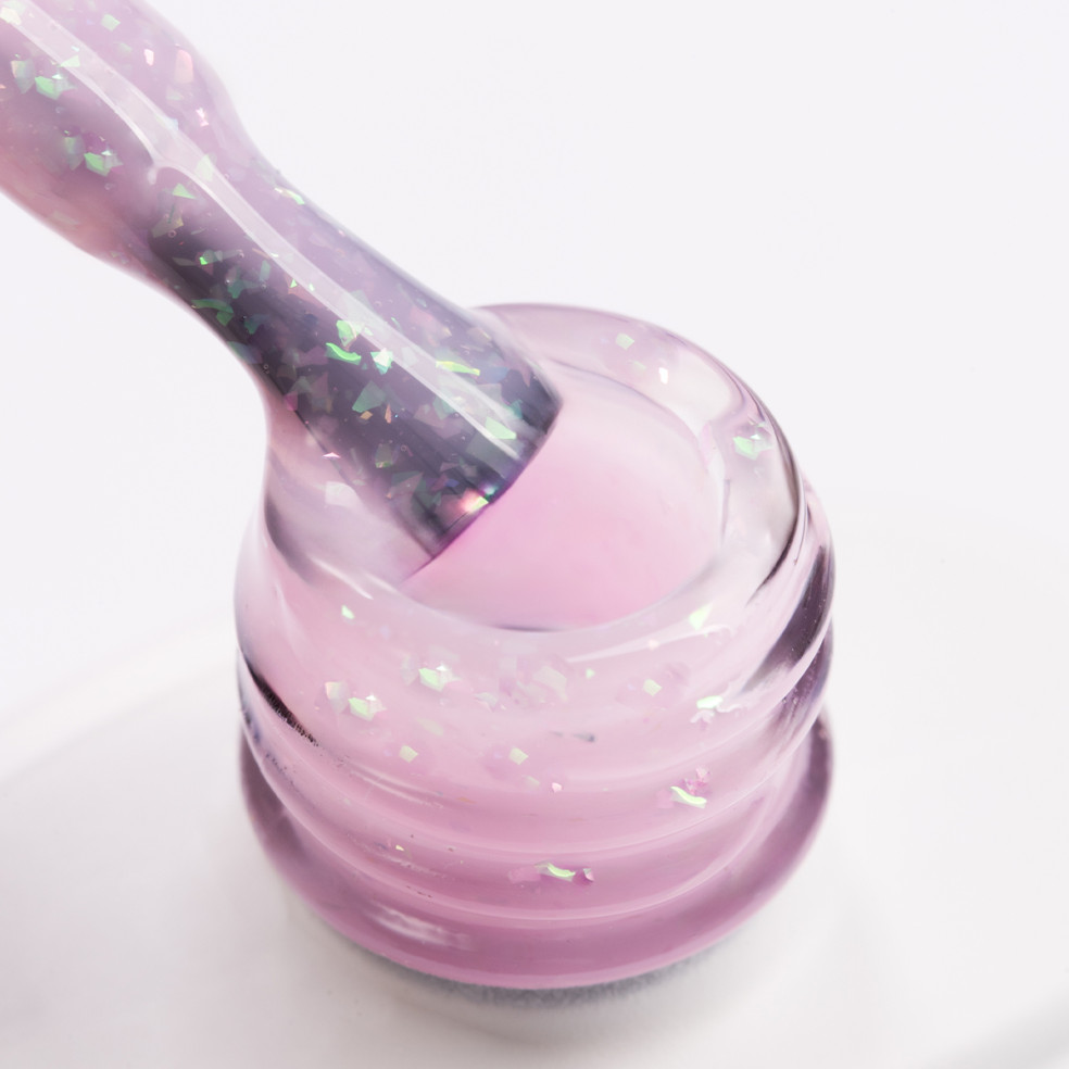 Pędzelek zanurzony w żelu do przedłużania paznokci w kolorze mlecznoróżowym z kawałkami ciętej folii