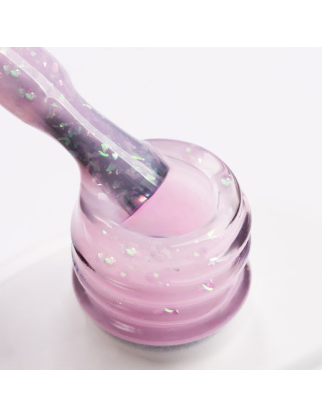 Pędzelek zanurzony w żelu do przedłużania paznokci w kolorze mlecznoróżowym z kawałkami ciętej folii