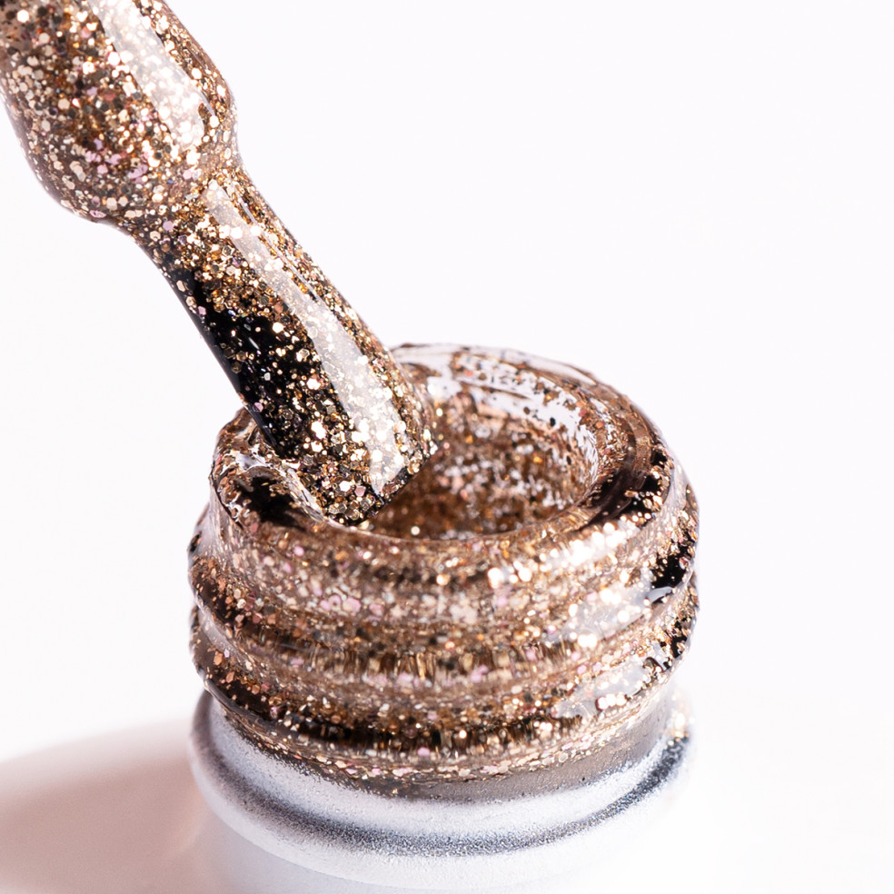 Pędzelek zanurzony w złotym brokatowym lakierze hybrydowym