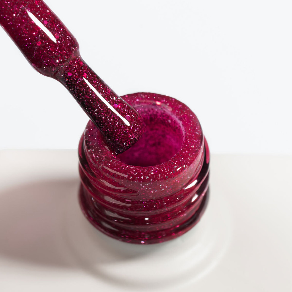 Zbliżenie na pędzelek lakieru hybrydowego NaiLac Glitterally! ukazujące malinowy róż z brokatem i efektem flash