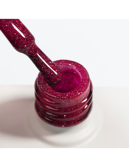 Zbliżenie na pędzelek lakieru hybrydowego NaiLac Glitterally! ukazujące malinowy róż z brokatem i efektem flash