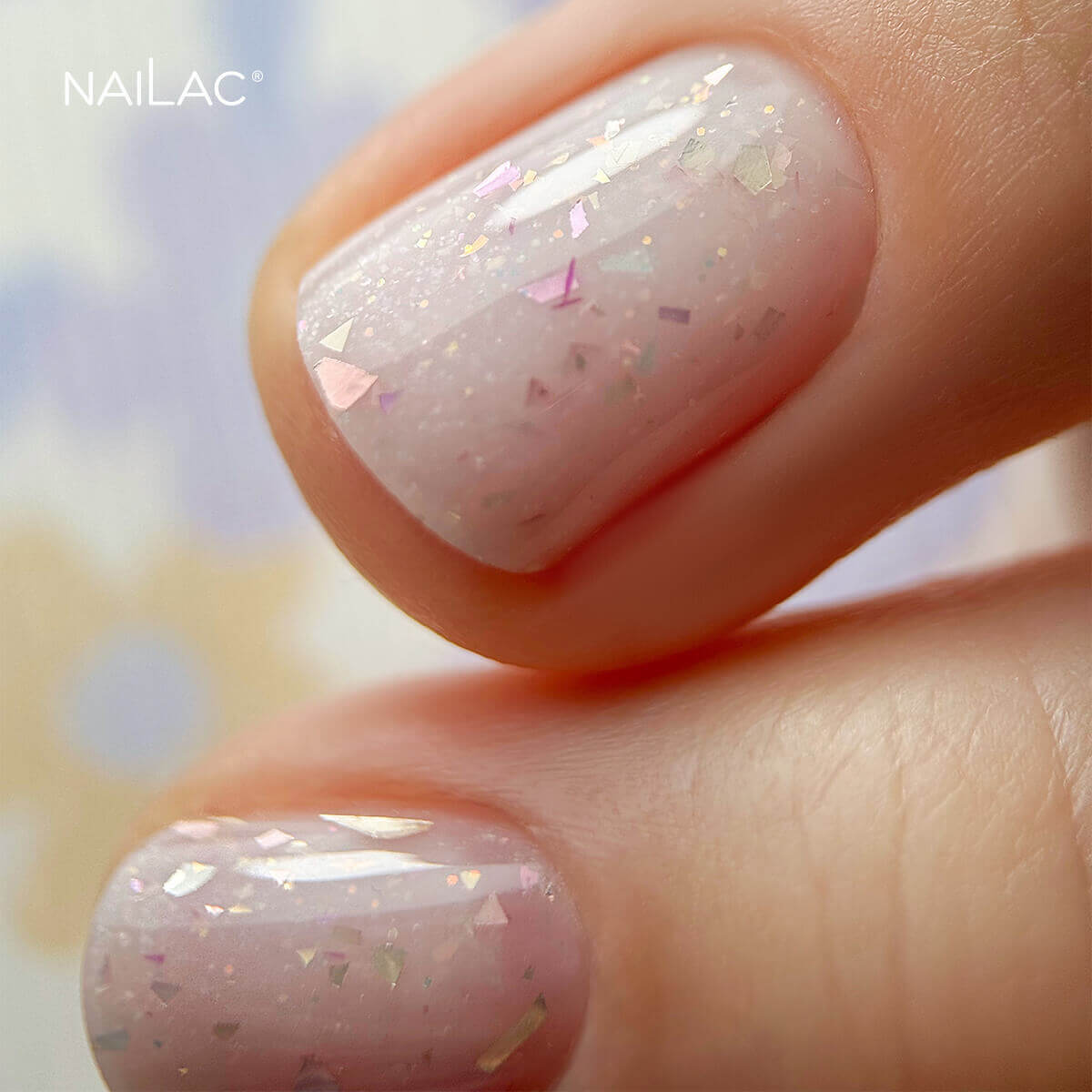 Manicure hybrydowy. Zbliżenie na paznokcie pokryte bazą kauczukową z drobinkami ciętej folii Glammy Base 
